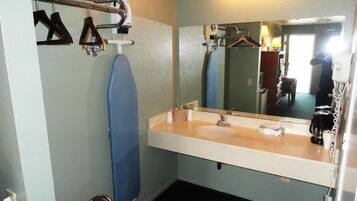 A bathroom with a sink, mirror, and towel rack.