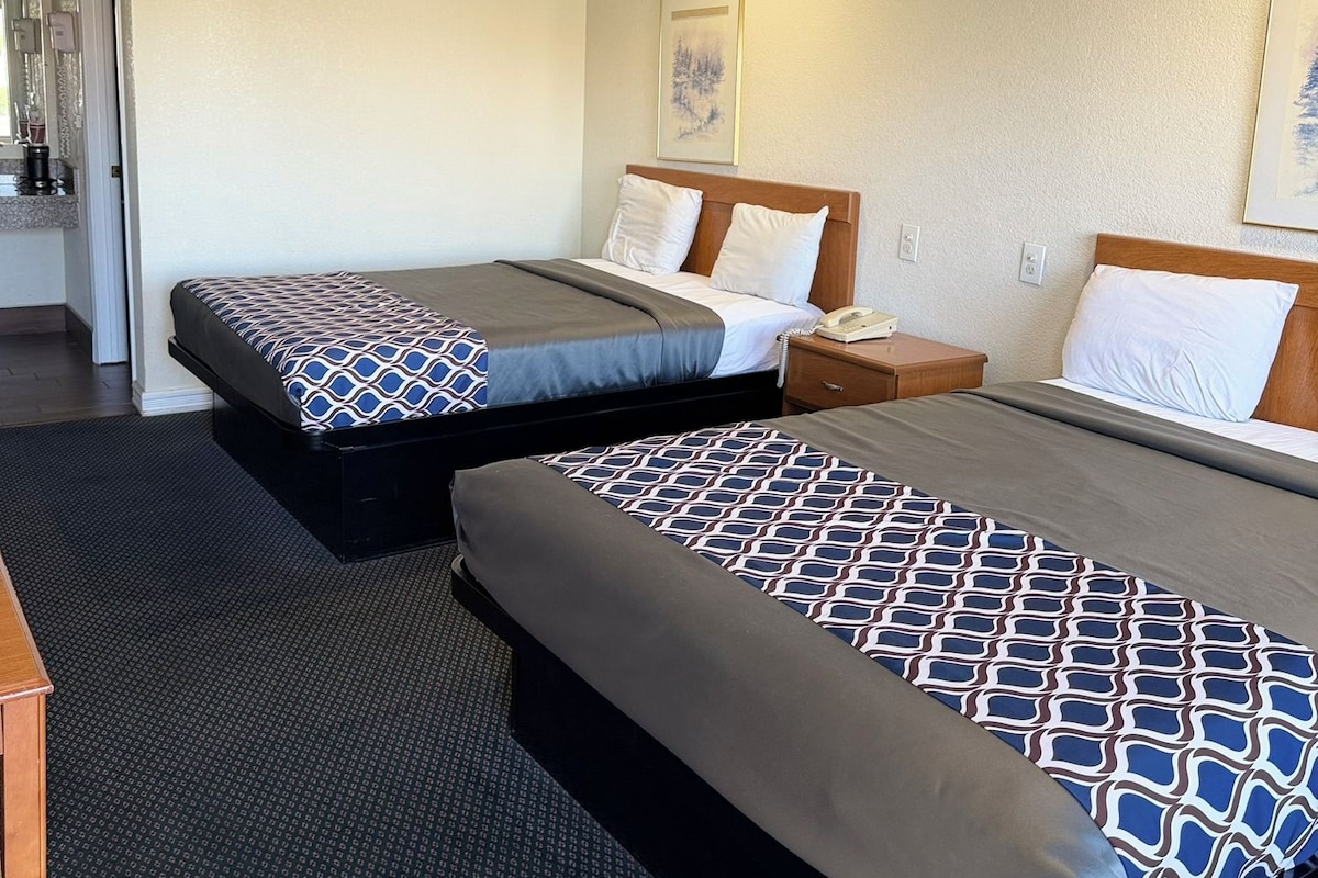 Une chambre d’hôtel avec deux lits, une petite table de chevet avec un téléphone et un luminaire fixé au mur.