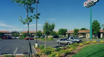 Un estacionamiento con varios coches, un cartel de Apple Inn y un edificio con techo rojo al fondo.