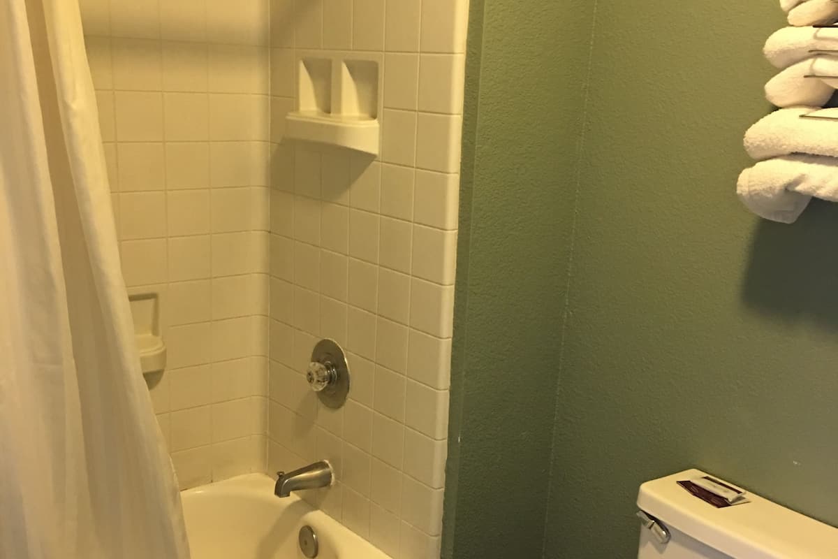 A bathroom with a bathtub, toilet, and a towel rack.