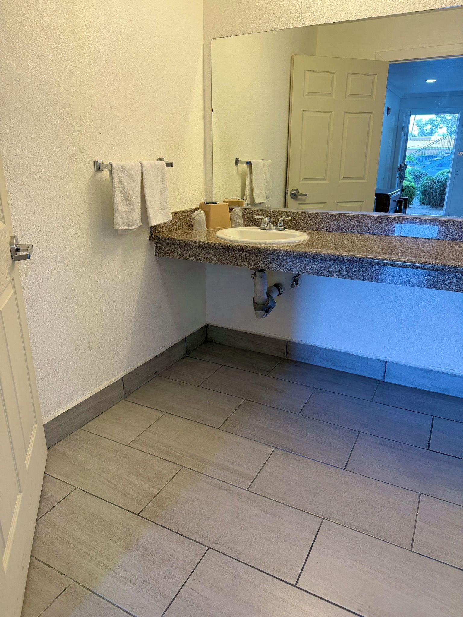 Un baño con lavamanos, espejo y perchero para toallas.