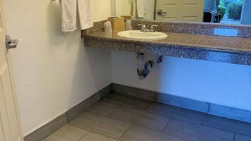 Un baño con lavamanos, espejo y perchero para toallas.