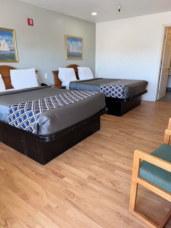 Une chambre d’hôtel avec deux lits, un plancher en bois et une chaise.