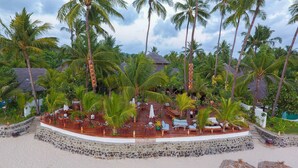 A resort with a wooden deck, lounge chairs, and a stone wall.