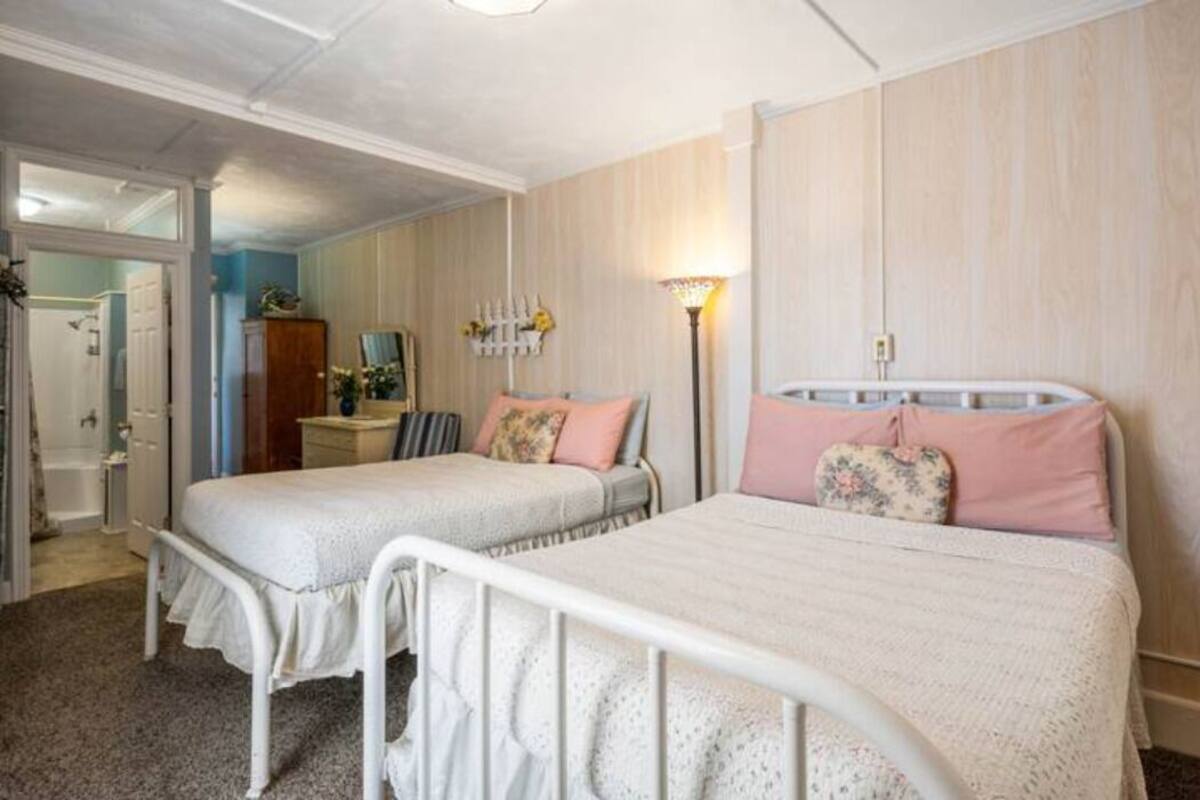 A bedroom with two single beds, a bedside table, a lamp, and a wardrobe.