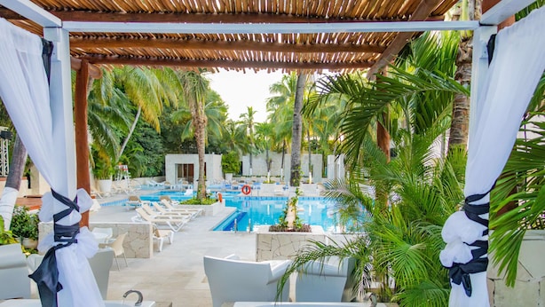 Un espace piscine avec des chaises longues et une pergola.