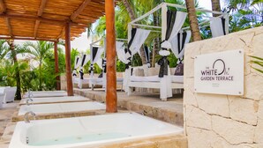 Une terrasse de jardin agrémentée de plusieurs jardinières blanches, d’un mur en pierre et d’une enseigne indiquant : « La terrasse du jardin White Oh ! ».