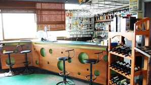 A bar area with stools, a wine rack, and shelves with bottles. - Hotel Pho Sein (Yangon)