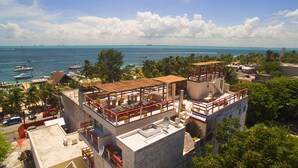 Un edificio de varios pisos con terraza en la azotea, piscina y vistas al océano.