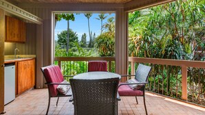 Un patio techado con techo de madera, una mesa de comedor con sillas y vistas a un jardín exuberante.