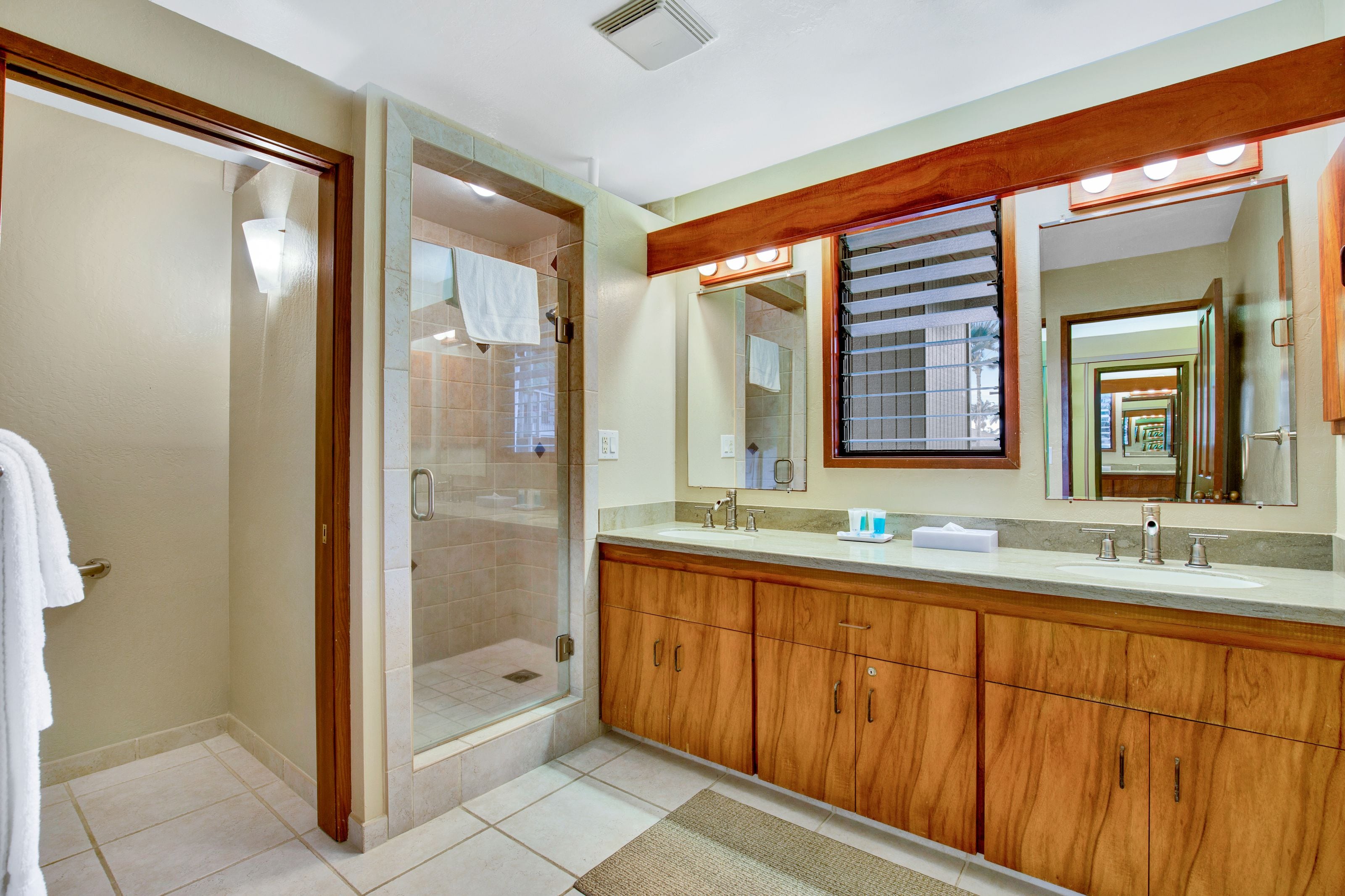 A bathroom with a walk-in shower, wooden cabinets, a large mirror, and a vanity with a sink.