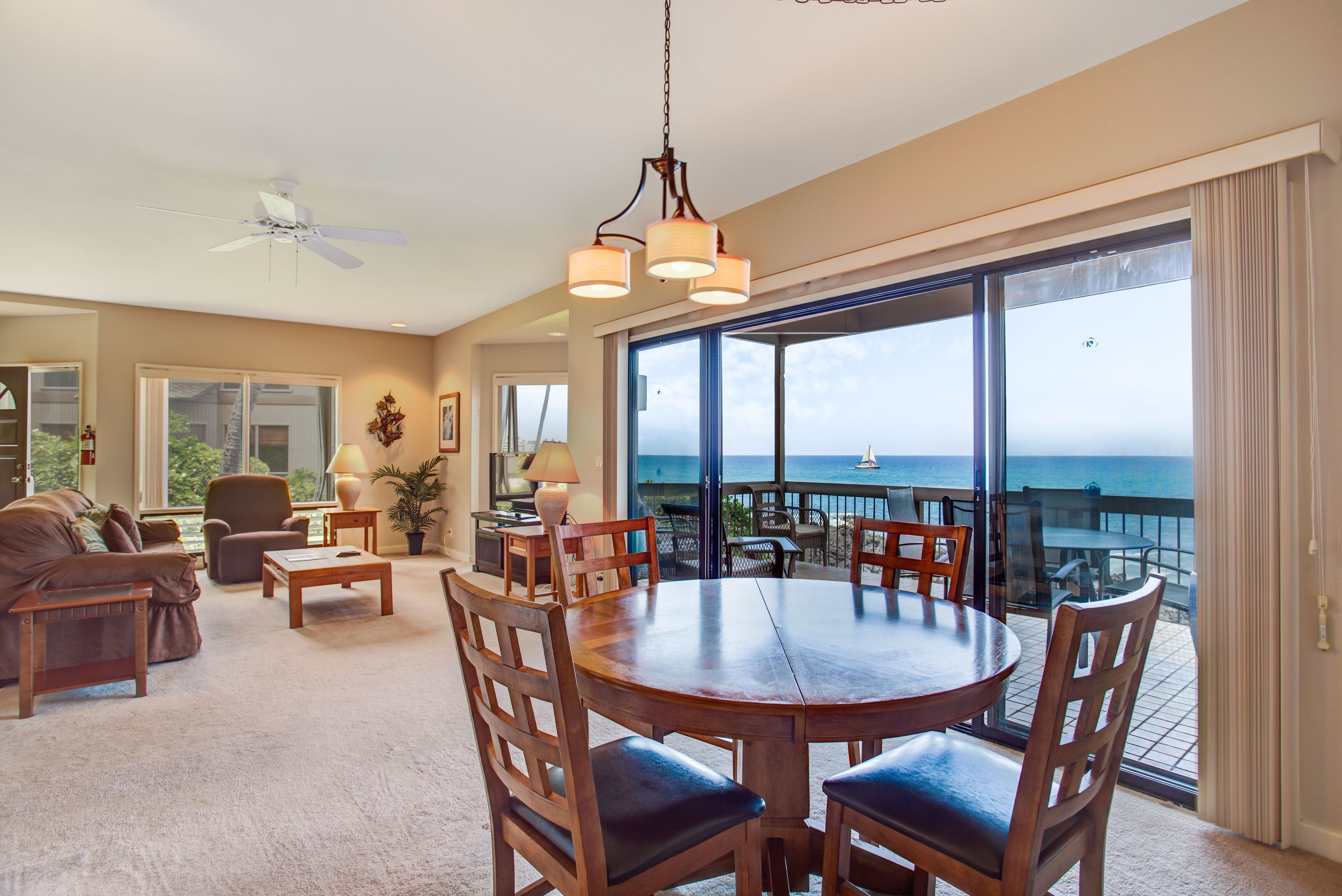 A spacious living room with a large round table, comfortable seating, and a view of the ocean through large windows.
