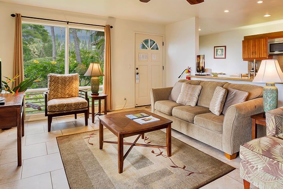 A living room with a sofa, armchairs, a coffee table, and a view of the outdoors through a sliding door.
