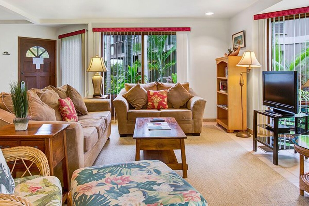 A living room with two sofas, a coffee table, a TV, and a bookshelf.