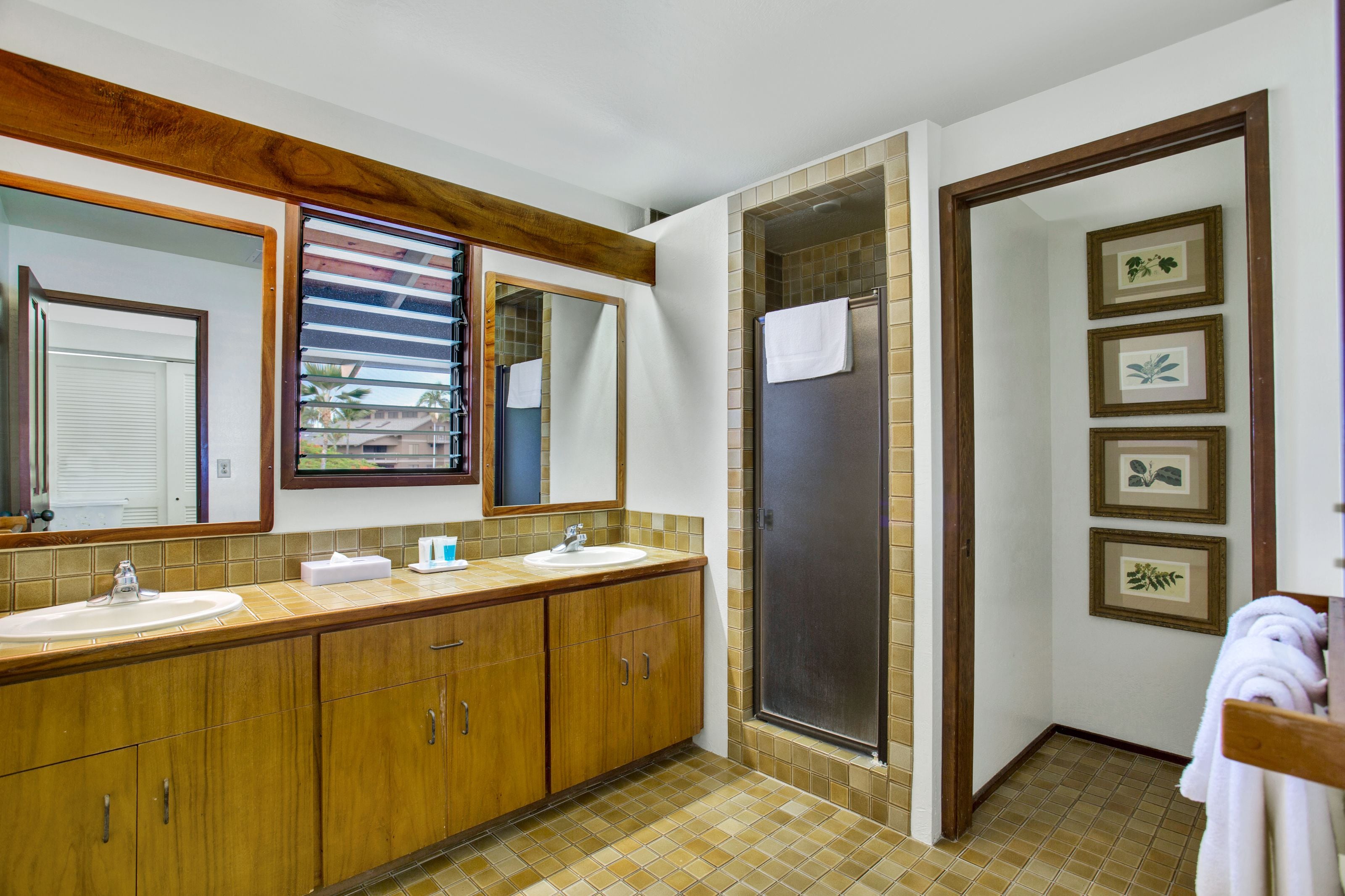 A bathroom with a wooden vanity, two sinks, a large mirror, and a shower area.