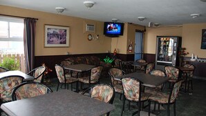 Un restaurante con cabinas y mesas, un televisor montado en la pared y un refrigerador.