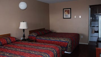 A hotel room with two beds, a lamp, a framed picture on the wall, and a refrigerator.