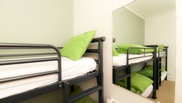 A bunk bed room with green pillows and a mirror on the wall.