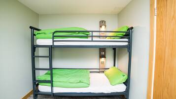 Ein Stockbett mit grüner Bettwäsche und einer Wandleuchte.