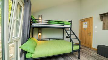 A bunk bed room with a window, a door, and a small bench.