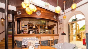 Un rincón de bar acogedor con mobiliario de madera y luces colgantes.