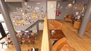 A modern lounge area with a high ceiling, wooden flooring, and a variety of seating options including sofas and chairs. - YHA Bristol - Hostel (Bristol)