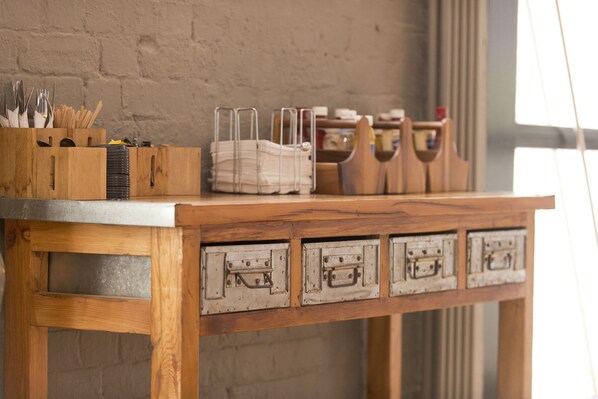 Una mesa de madera con cajones metálicos y un escurridor de utensilios.