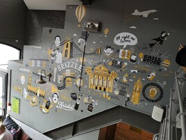Una pared con diversos adhesivos y dibujos, incluyendo un puente, edificios y texto relacionado con Bristol.