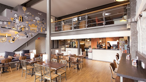 A modern restaurant with a mezzanine level, wooden flooring, and a variety of seating options including tables and chairs. - YHA Bristol - Hostel (Bristol)