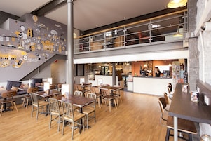 Un restaurante moderno con un entresuelo, suelo de madera y diversas opciones de asientos, incluyendo mesas y sillas.