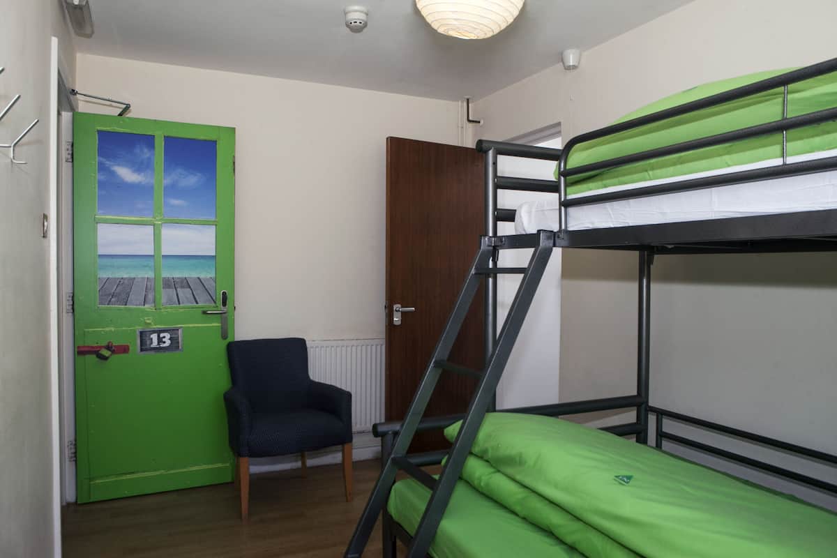 A room with bunk beds, a chair, and a door with a number.