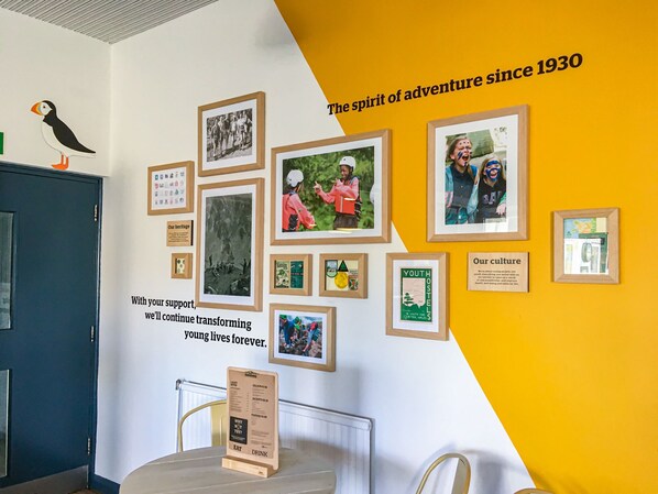 A wall with framed photos and text, a wooden signboard, and a pufferfish decoration.