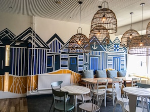 A restaurant with a nautical-themed wall mural, wicker pendant lights, and a variety of seating options including tables and chairs. - YHA Broad Haven - Hostel (Haverfordwest)