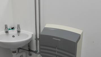 A bathroom with a white sink, a toilet, and a paper towel dispenser mounted on the wall.