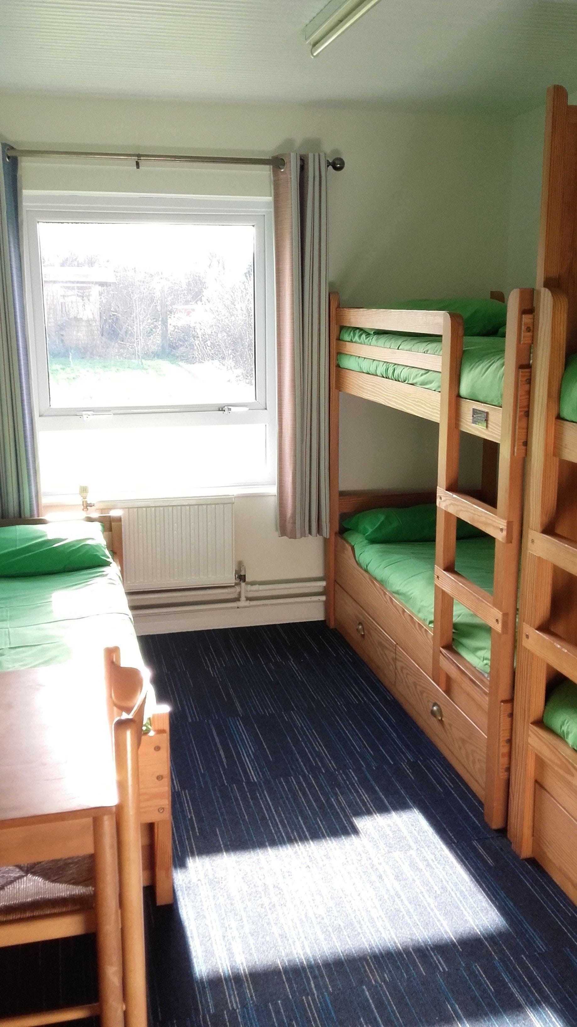 A compact room with bunk beds, a table, and a window.