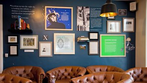 A room with leather sofas, framed pictures, and a table with a bottle and menu.