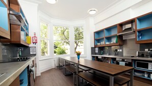 A modern kitchen with built-in appliances, a central island, and large windows offering a view of the outdoors.