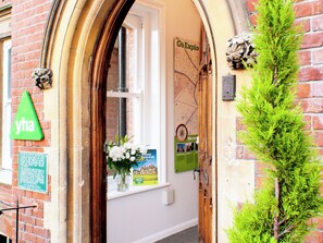 A hotel entrance with a wooden archway, a green 'yha' sign, a window with a view, and a small green plant beside the door. - YHA Canterbury - Hostel (Canterbury)