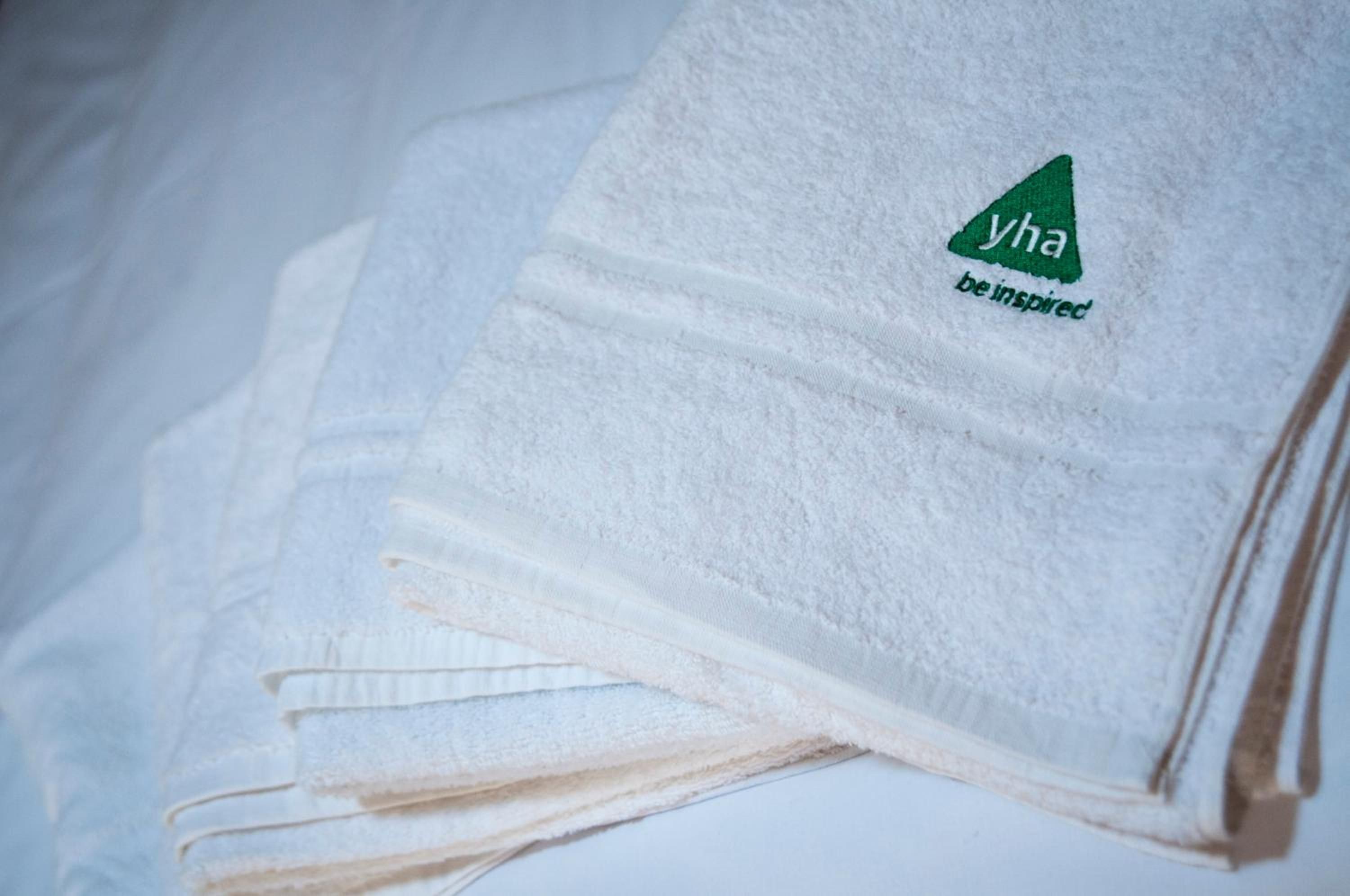A stack of white towels with a logo and text on them.