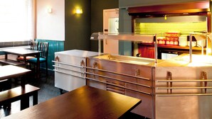 Un ristorante con un bancone, una sala e una cucina visibile tramite una parete di vetro.