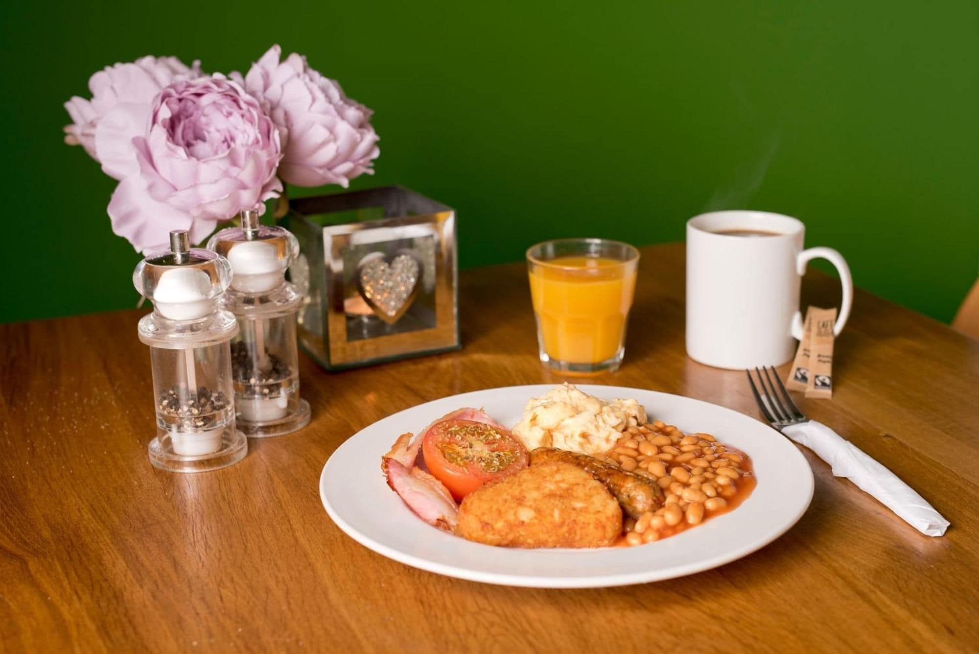 A breakfast plate with eggs, beans, and tomato on a wooden table.