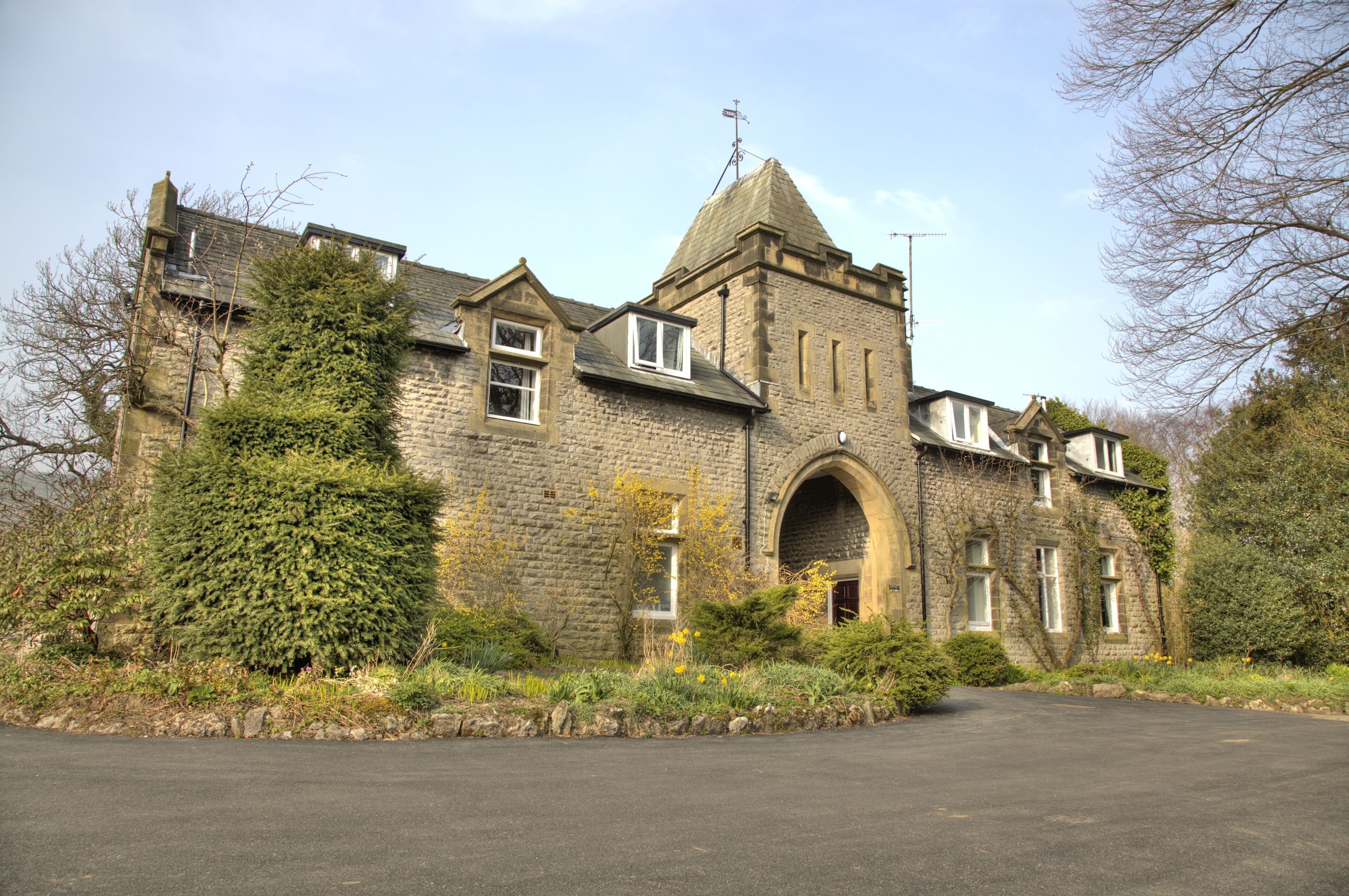 A stone building with a prominent arched entrance, multiple windows, and a chimney.