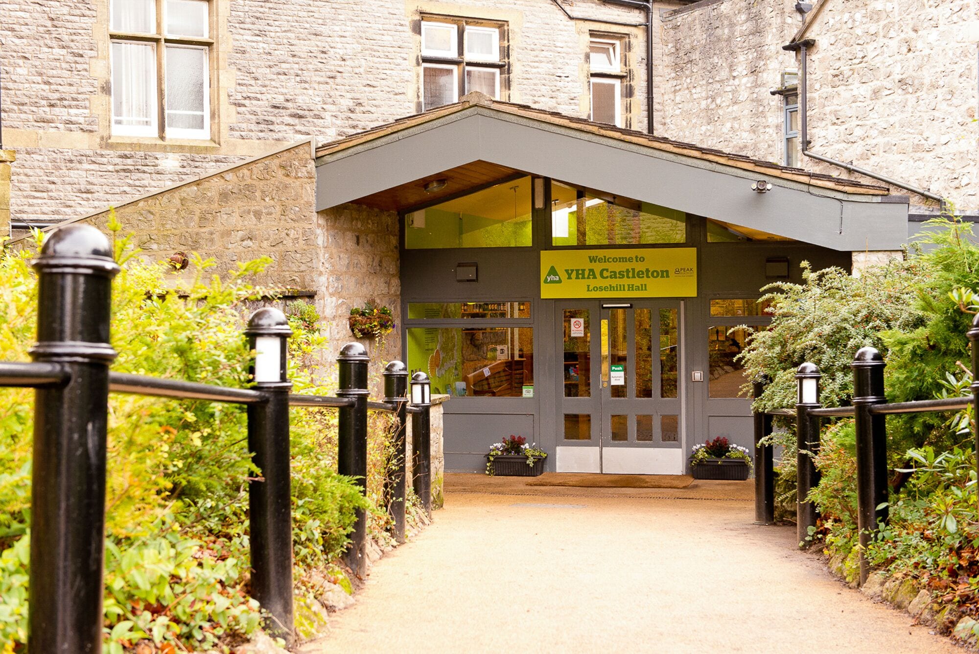 A building entrance with a sign reading "Welcome to YHA Castleton Losehill Hall."