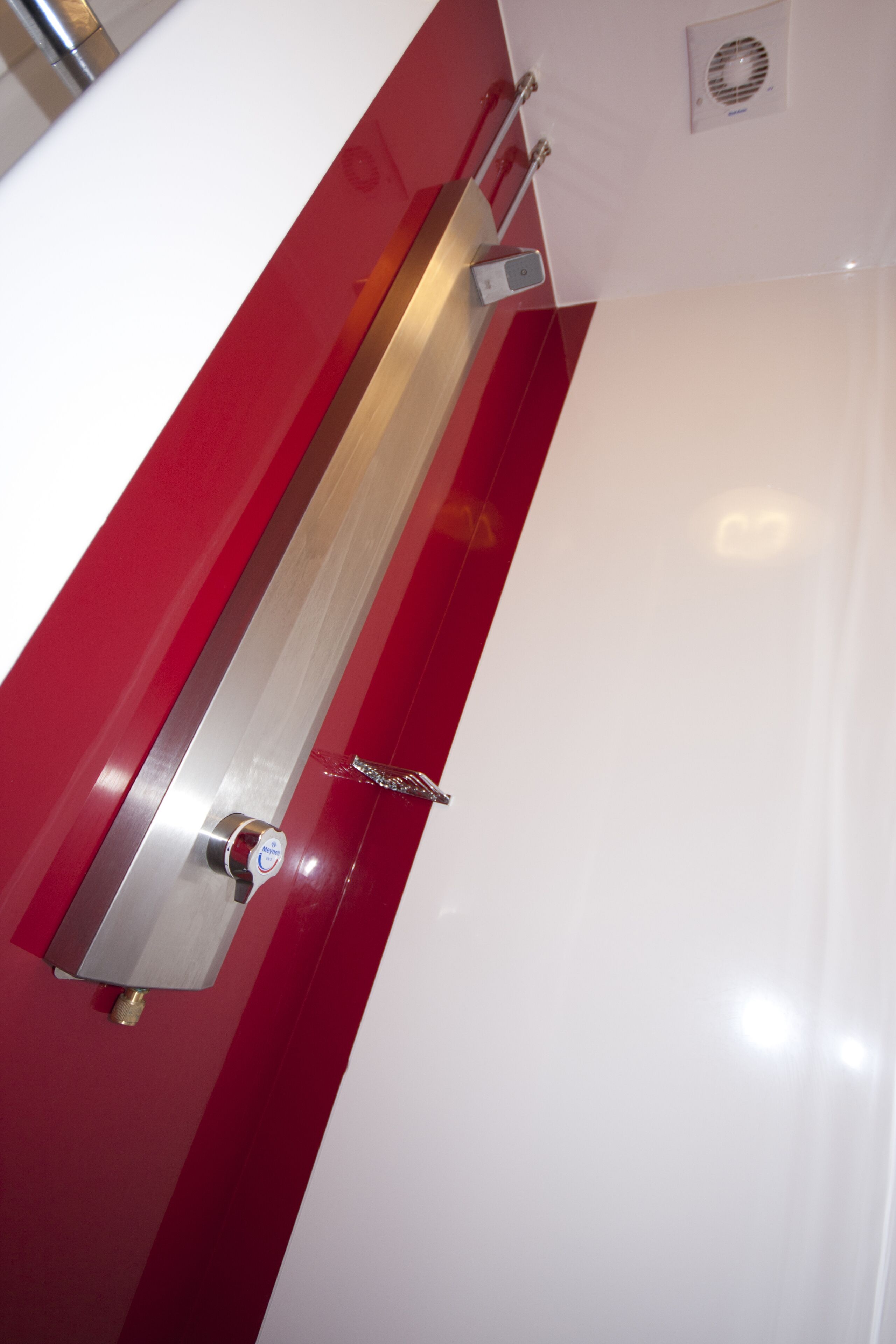 A metallic handle and a keyhole on a white and red wall.