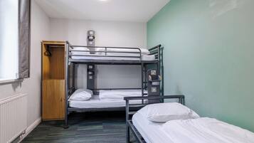 Dormitorio con literas, un radiador, toma de corriente y una puerta.