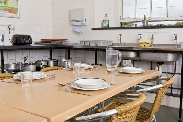 Une cuisine avec une table en bois mise pour le repas, agrémentée d’assiettes, de verres et de couverts.