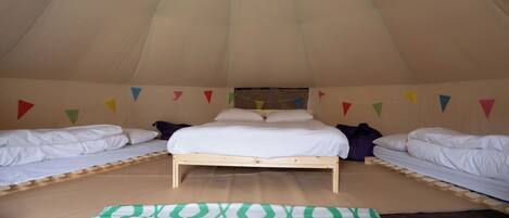 A tent with a single bed and two smaller beds.