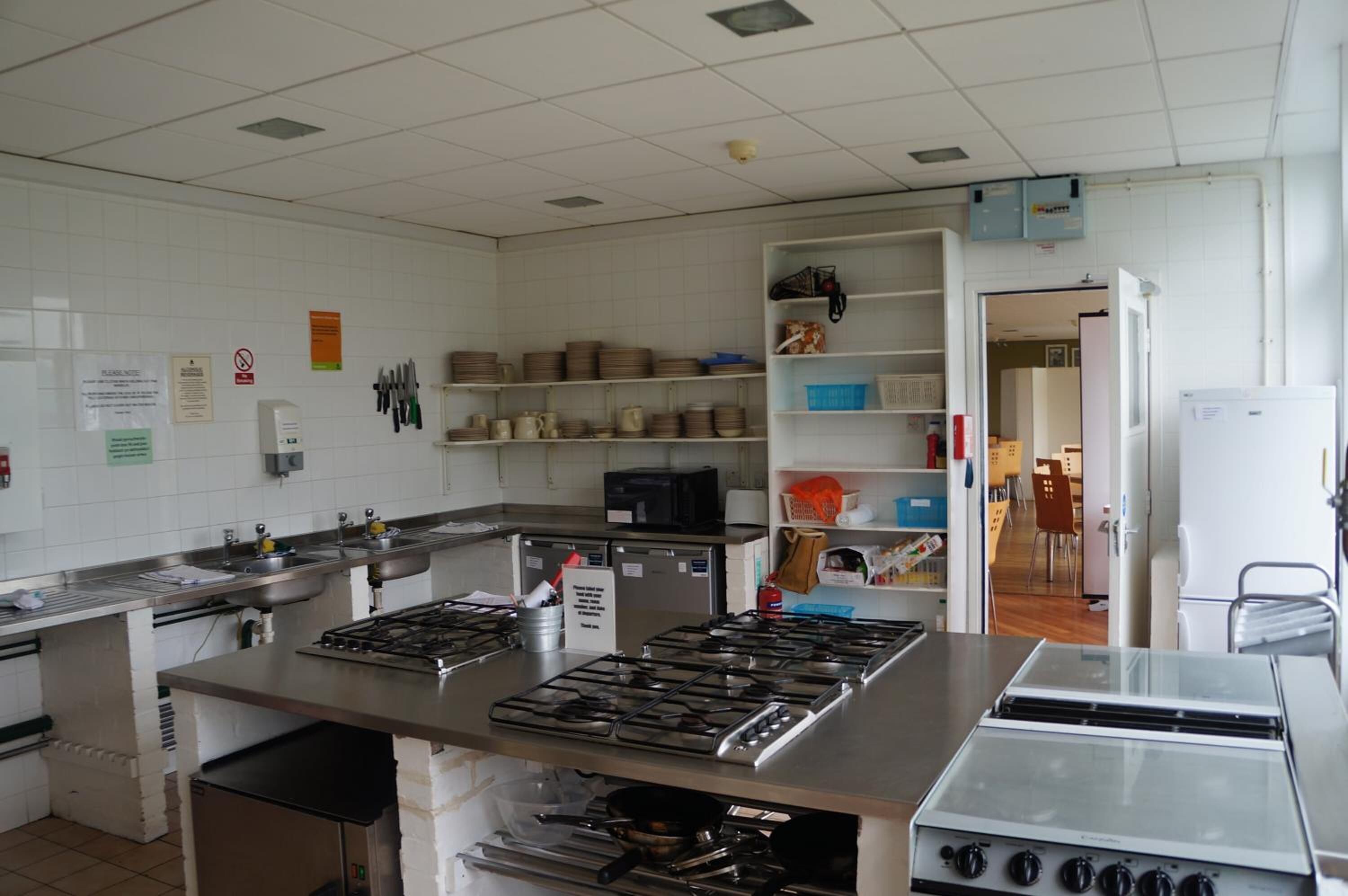 A kitchen with stainless steel appliances, a sink, and various kitchen utensils on shelves.