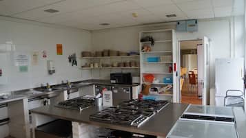 Una cocina con electrodomésticos de acero inoxidable, un fregadero y diversos utensilios de cocina en estantes.