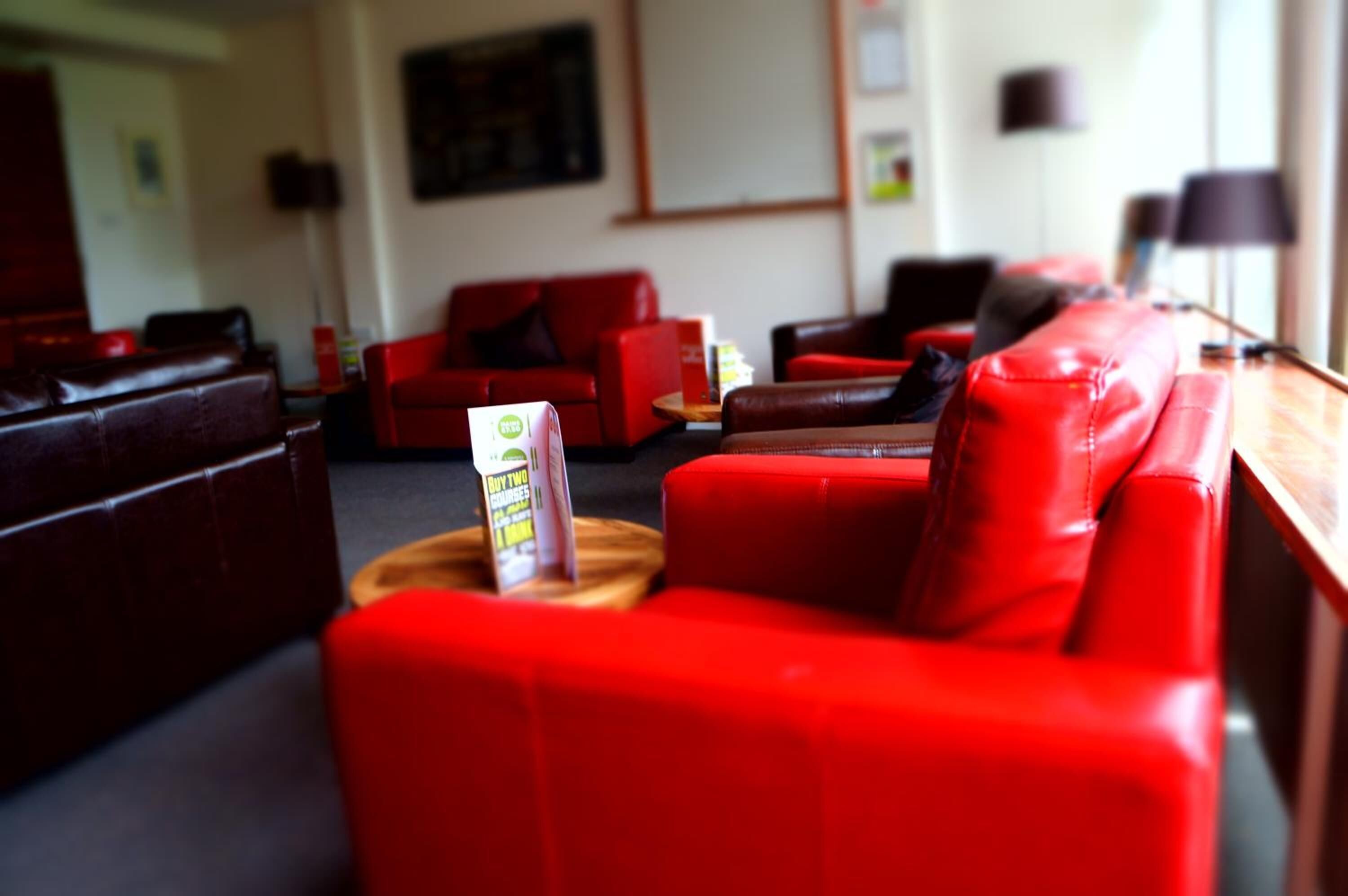 Una sala moderna con sofás de cuero rojo y una mesa de centro de madera.